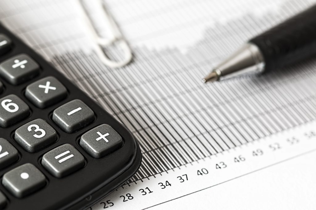 Reduce financial anxiety by staying engaged with your finances. Pictured: calculator and a pen on top of a chart