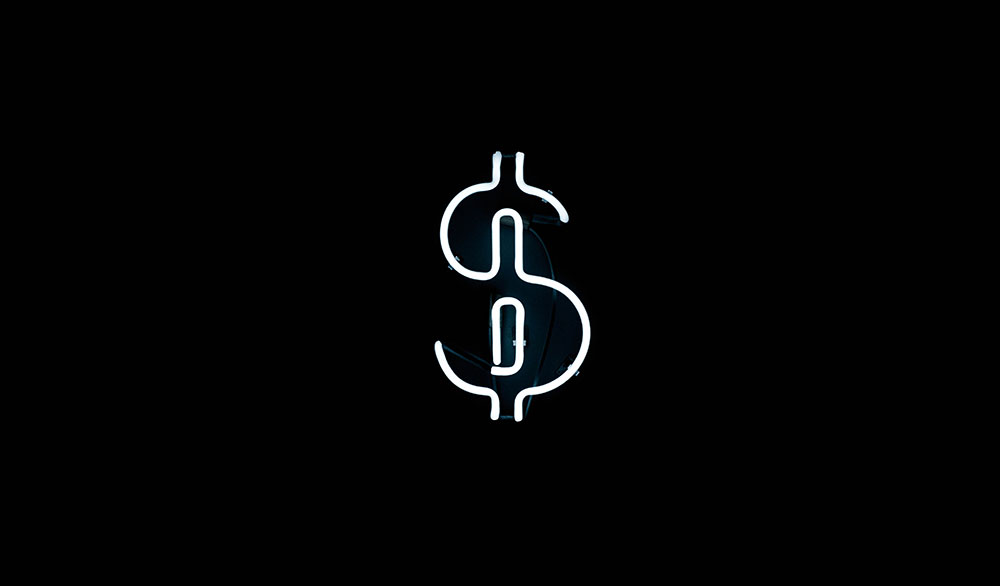 A white neon dollar sign against a black wall