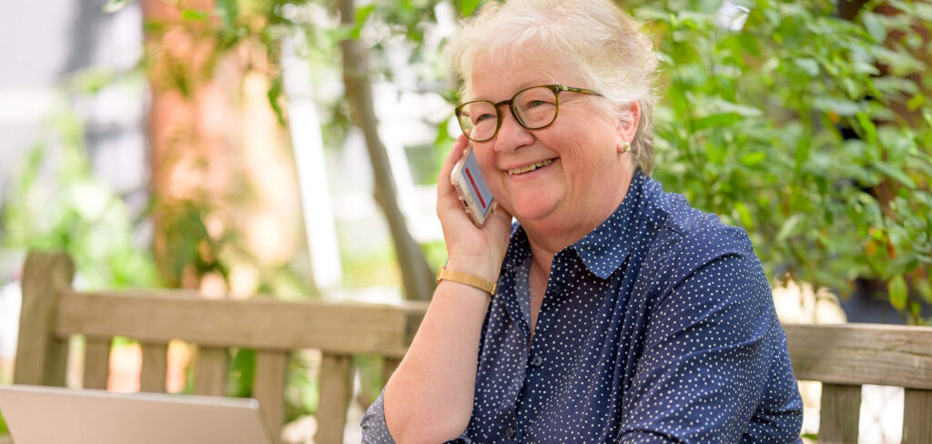 Understanding target audience: an older woman talks on a cell phone with her laptop open in front of her