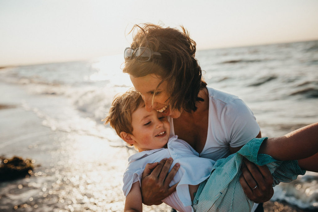 Women in finance: Women can only feel financially secure when their loved ones are taken care of. Here a woman carries her son on the beach--both are smiling
