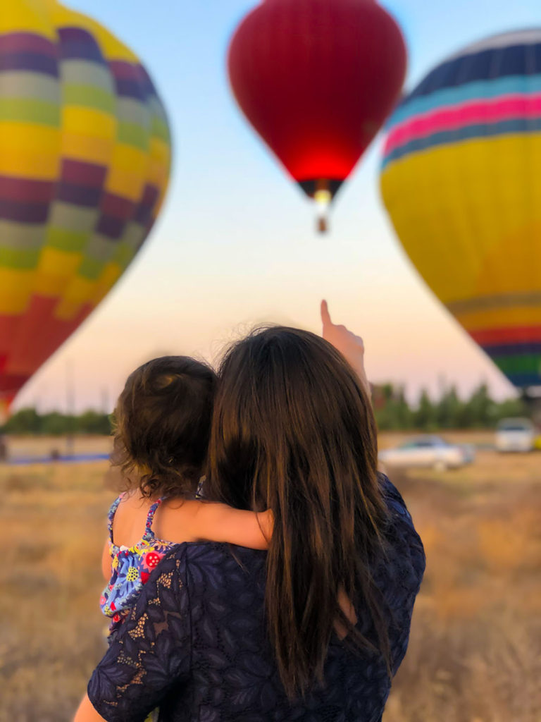 Women in Finance: women focus on investing to achieve specific goals that impact people important in their lives: their education, their children’s education, or their retirement. Here, a woman points out a hot air balloon to her daughter