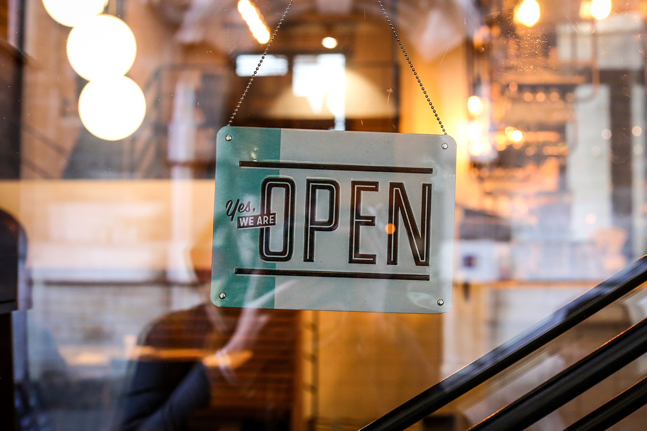 Business owners optimistic: A sign reading "Yes, we're open" hangings inside a glass window