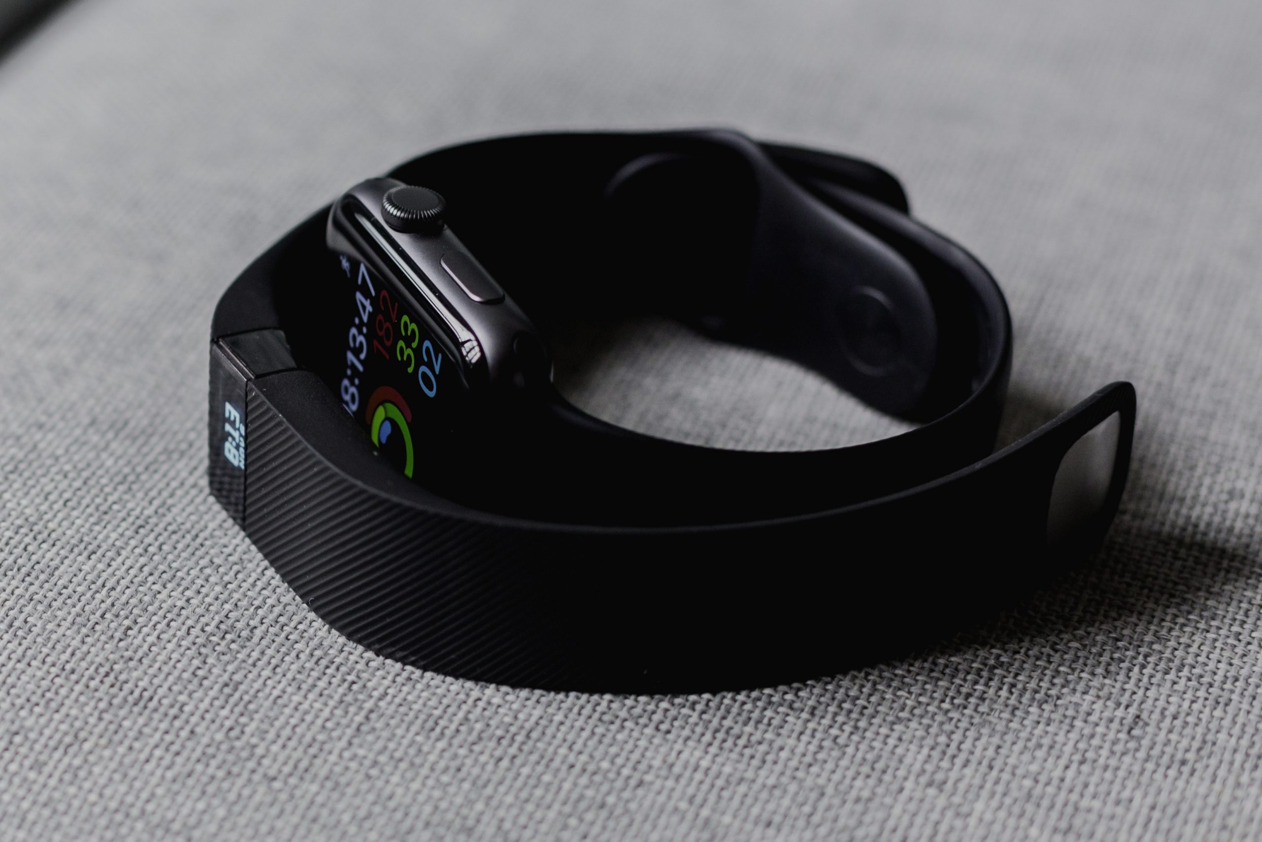 An Apple Watch surrounded by a FitBit -- wearable tech