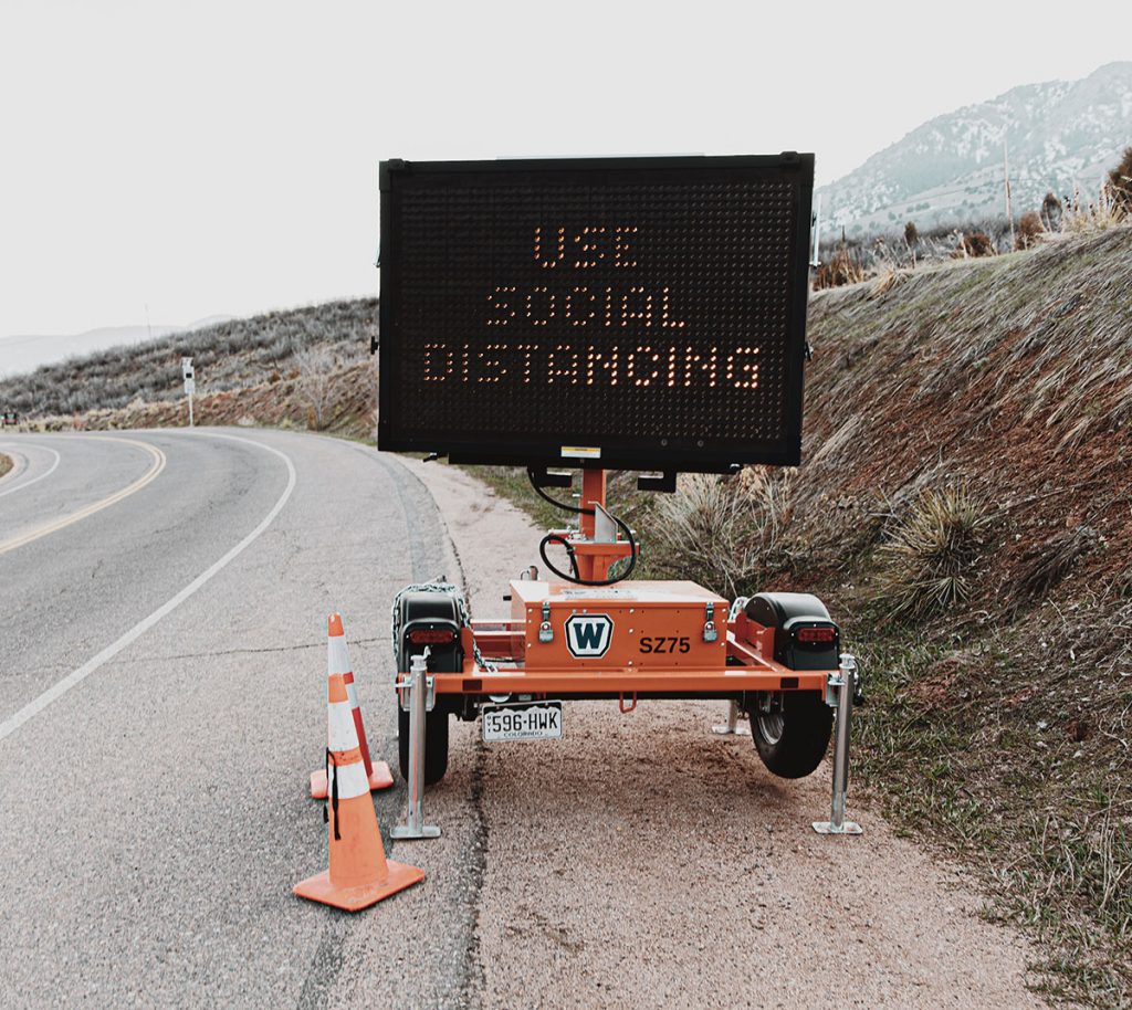 A digital street-side sign reads "use social distancing"