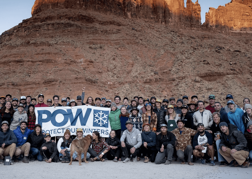 Protect Our Winters group with a sign in front of a rock formation