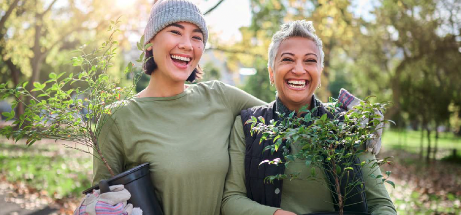 A younger woman and a more mature woman hold plants outdoors