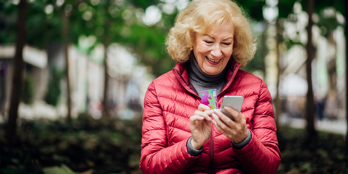 Decumulation in retirement: An older woman pays for something on her mobile phone