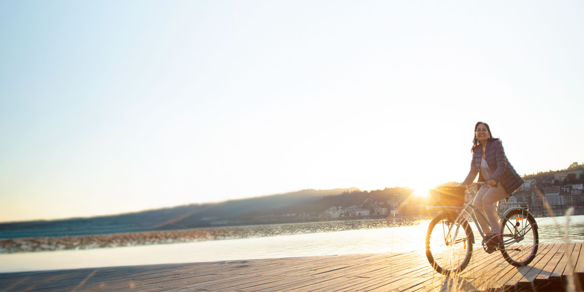 Gen Xers in retirement: A woman riding her bike on the beach at sunrise